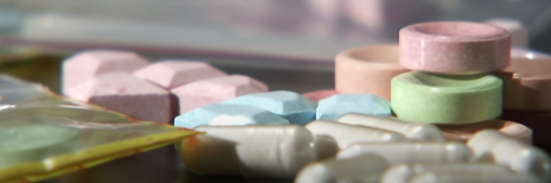 Разноцветные таблетки и капсулы рассыпаны по поверхности